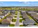 Expansive aerial shot displays a suburban neighborhood with well-maintained homes, green spaces, and a nearby lake at 2170 Biller Cir, The Villages, FL 32163