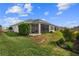Well-maintained backyard features lush green grass, decorative shrubs, and a screened-in patio at 2170 Biller Cir, The Villages, FL 32163