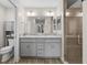 Bright bathroom featuring double sink vanity, gray cabinets, and a glass-enclosed shower at 2170 Biller Cir, The Villages, FL 32163