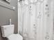Bathroom with a decorative floral shower curtain, grey wall, and neutral-colored wall tile at 2310 Silver Palm Dr # 301, Kissimmee, FL 34747