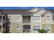 Exterior view of a multi-story, tan building with a screened-in balcony under a blue sky at 2310 Silver Palm Dr # 301, Kissimmee, FL 34747