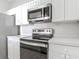 Modern kitchen featuring stainless steel oven, microwave, white cabinetry, and sleek countertops at 2310 Silver Palm Dr # 301, Kissimmee, FL 34747