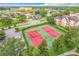 Aerial view of red and green tennis courts in a lushly landscaped community with surrounding neighborhood at 2310 Silver Palm Dr # 301, Kissimmee, FL 34747