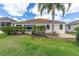 Landscaped backyard featuring a well-maintained lawn, brick paver patio, lush bushes, and a mature palm tree at 278 Matisse Ave, The Villages, FL 32162