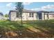 View of a charming backyard with a young tree and covered patio at 28078 Poppy Ct, Leesburg, FL 34748