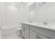 Bright bathroom with double vanity, grey cabinets, a tiled shower and a soaking tub at 28078 Poppy Ct, Leesburg, FL 34748