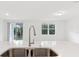 Close-up of kitchen island, faucet, and sink; window and sliding glass door to backyard in background at 28078 Poppy Ct, Leesburg, FL 34748