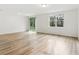 Bright and airy living room featuring wood-look floors, a large window, and sliding glass door to patio at 28078 Poppy Ct, Leesburg, FL 34748