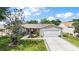 Inviting single-story home featuring a well-manicured lawn, a two car garage, and charming curb appeal in a suburban neighborhood at 299 Jefferson Ln, The Villages, FL 32162