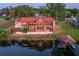 Beautiful aerial view of waterfront home with a red tile roof, lush landscaping, and private dock at 3011 Lake Woodward Dr, Eustis, FL 32726