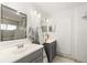 This well-lit bathroom includes a large mirror, dual sinks, gray cabinets, plantation shutters, and updated fixtures at 3011 Lake Woodward Dr, Eustis, FL 32726