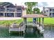 Water view of a boat dock and lift, situated on calm water with the house and screened in patio in the background at 3011 Lake Woodward Dr, Eustis, FL 32726