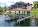 View of a boat dock with lift, situated on calm water with the house and screened in patio in the background at 3011 Lake Woodward Dr, Eustis, FL 32726