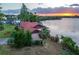 Waterfront home with lush landscaping, a private dock, and a scenic sunset backdrop at 3011 Lake Woodward Dr, Eustis, FL 32726