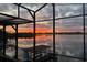 Scenic water view from the enclosed porch, featuring a covered dock and colorful sunset at 3011 Lake Woodward Dr, Eustis, FL 32726