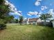 Expansive backyard with green lawn, partial fence, trees, and a blue sky at 3051 Newmark Dr, Deltona, FL 32738