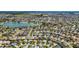 Aerial shot showcases a community of houses, surrounded by a lake and verdant green spaces at 3203 Islawild Way, The Villages, FL 32163