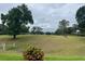 View of the lush, green golf course surrounded by mature trees under a cloudy sky at 3708 Fairfield Dr, Clermont, FL 34711