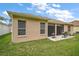 A view of the backyard with a small patio, a barbecue grill, and lush green grass at 3828 Arbordale Ct, Leesburg, FL 34748
