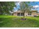 Backyard featuring patio with outdoor seating, mature trees, and green grass at 3828 Arbordale Ct, Leesburg, FL 34748