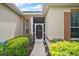 Front entryway with a decorative glass storm door surrounded by green bushes at 3828 Arbordale Ct, Leesburg, FL 34748
