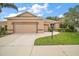 Well maintained tan single story home with large driveway and manicured lawn at 3828 Arbordale Ct, Leesburg, FL 34748