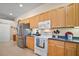 Efficient kitchen featuring stainless steel refrigerator, light cabinets, and white appliances at 3828 Arbordale Ct, Leesburg, FL 34748