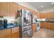 Bright kitchen featuring stainless steel refrigerator, light wood cabinets, and tile flooring at 3828 Arbordale Ct, Leesburg, FL 34748