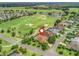 Aerial view showcases a home on a golf course with a pin; scenic community featuring lush greenery and a tranquil lake at 383 Kilmer Way, The Villages, FL 32162