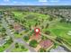 Aerial view showcases a home on a golf course with a pin; scenic community featuring lush greenery and a tranquil lake at 383 Kilmer Way, The Villages, FL 32162