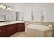 Relax in the luxurious main bathroom featuring a soaking tub and dual vanities for ultimate comfort and convenience at 38716 Oak Place Ct, Lady Lake, FL 32159