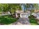 Charming home with a well-manicured lawn, landscaping, mature trees, and a paver driveway at 411 Loma Paseo Dr, The Villages, FL 32159