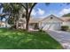 Charming single-story home with a well-maintained lawn, mature trees and brick-paved driveway leading to a two car garage at 411 Loma Paseo Dr, The Villages, FL 32159