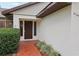 Close-up of a home's front entrance with a brick pathway, manicured bushes, and glass sidelights by the door at 4145 Dora Wood Dr, Mount Dora, FL 32757