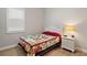 Cozy bedroom with wood floors, a colorful quilt, and a nightstand with a lamp at 5195 Greens Dr, Lady Lake, FL 32159