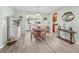 Bright dining area with wood floors, a stylish table, and a view to the sunroom at 530 Valencia Pl, The Villages, FL 32159
