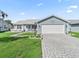Charming single-story home with blue siding, a brick driveway, and well-manicured lawn at 530 Valencia Pl, The Villages, FL 32159