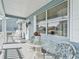 Cozy front porch featuring a glass table, wicker chairs, and views of the neighborhood at 530 Valencia Pl, The Villages, FL 32159