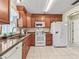 Well-lit kitchen with cherry cabinets, tile flooring, granite countertops, and white appliances at 530 Valencia Pl, The Villages, FL 32159
