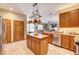 Open kitchen featuring wooden cabinets, a center island with pot rack, and tile flooring at 605 Westview Dr, Minneola, FL 34715