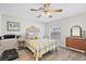 Cozy bedroom with wood-look floors, ceiling fan, and queen bed with decorative headboard and treadmill at 623 Delgado Ave, The Villages, FL 32159