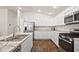 This kitchen offers white cabinetry, stainless steel appliances, marble countertops, and attractive wood flooring at 6248 Siverson Ter, The Villages, FL 32163