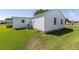 View of backyard and home's exterior, with a well-maintained lawn and an AC unit at 705 Prado Dr, The Villages, FL 32159