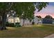 Charming single-story home with mature trees and manicured landscaping at dusk at 705 Prado Dr, The Villages, FL 32159