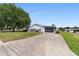 Charming home features a well-maintained lawn, a long brick driveway, and a screened-in porch at 705 Prado Dr, The Villages, FL 32159