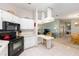 Open kitchen with white cabinets, bar seating, and a view of the living room at 705 Prado Dr, The Villages, FL 32159