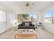 Sunlit living room boasts a cozy couch, glass coffee table, and neighborhood views at 705 Prado Dr, The Villages, FL 32159
