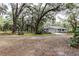 Exterior view of the home set among mature trees, showcasing the property's curb appeal at 7938 Jacksons River Rd, Leesburg, FL 34788
