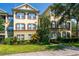 Multi-story condo with a manicured lawn, colorful bushes, and brown shutters surrounded by a walkway at 8256 Maritime Flag St # 103, Windermere, FL 34786