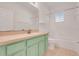 Bathroom with green vanity, large mirror, and bathtub at 9081 Saint Andrews Way, Mount Dora, FL 32757